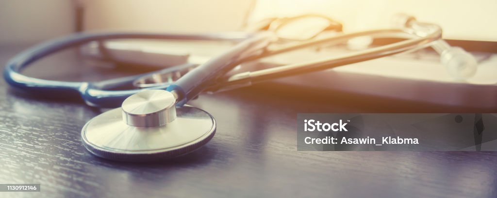 Stethoscope and laptop keyboard on desktop in hospital,relax time doctor,medical concept,selective focus,vintage color.morning light,banner Healthcare And Medicine Stock Photo