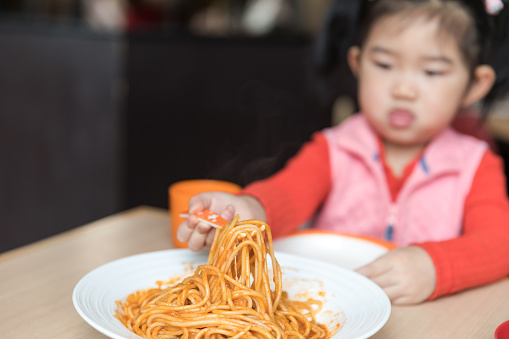 Cute baby girl eating spaghetti