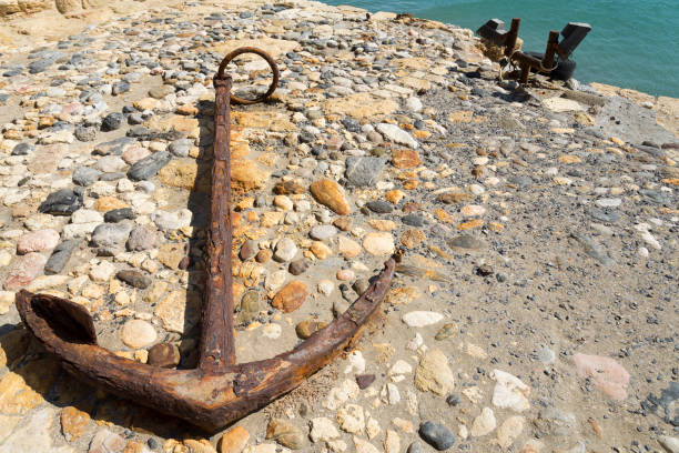 istock Old anchor lies on stones. Sunny day 1130915929