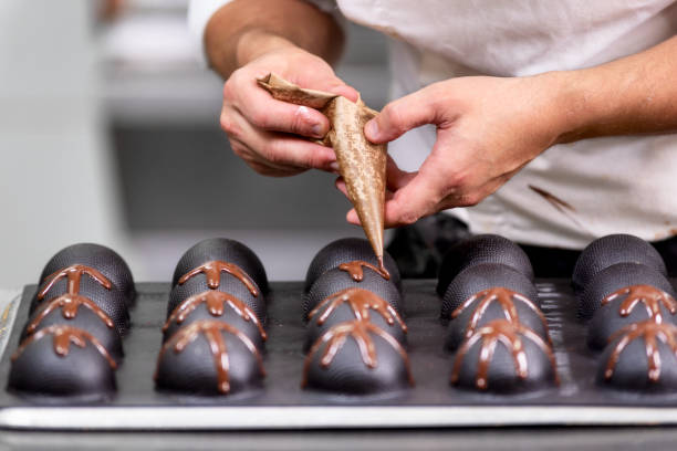 pastelero profesional haciendo dulces de chocolate en confitería. - food industry manufacturing human hand fotografías e imágenes de stock