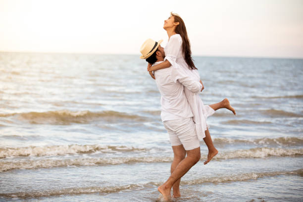 istock Man Carrying Woman While Wading In Sea Against Sky 1130916504