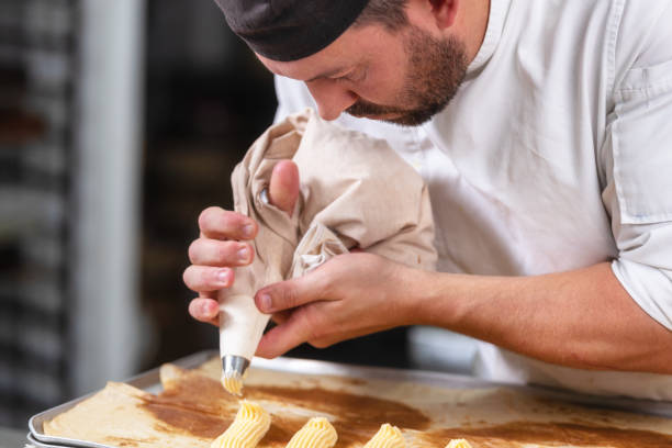 istock Pastry Chef with confectionary bag squeezing cream at pastry shop. 1130916699