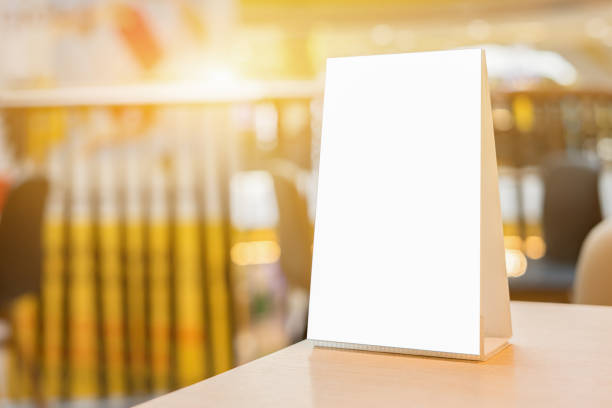 istock Mock up Menu frame on Table in Bar restaurant ,Stand for booklets with white sheets of paper acrylic tent card on cafeteria blurred background 1130917000
