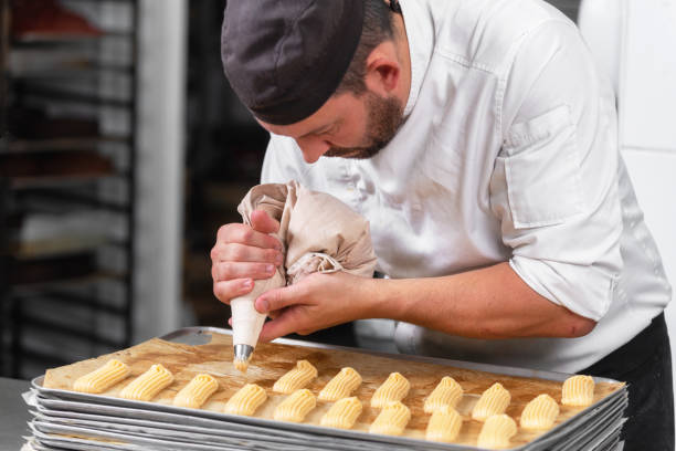 istock Pastry Chef with confectionary bag squeezing cream at pastry shop. 1130917880