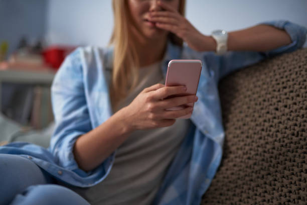 istock Young lady in blue shirt using smartphone at home 1130918844