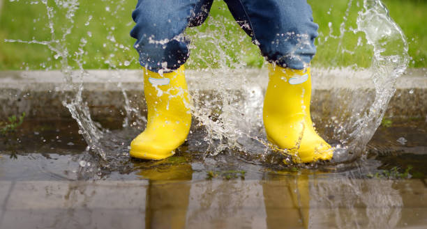 Toddler jumping in pool of water at the summer or autumn day Toddler jumping in pool of water at the summer or autumn day. Outdoors activity for kids. puddle photos stock pictures, royalty-free photos & images