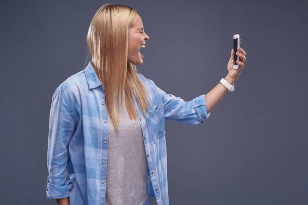 istock Emotional young lady with cellphone closing eyes and screaming 1130922629