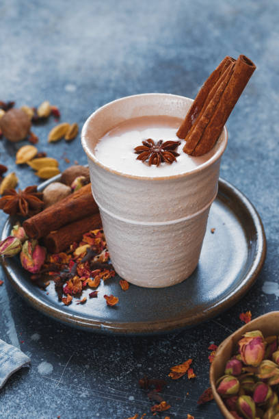 Spiced traditional Indian masala chai tea in cup with spices on rustic background