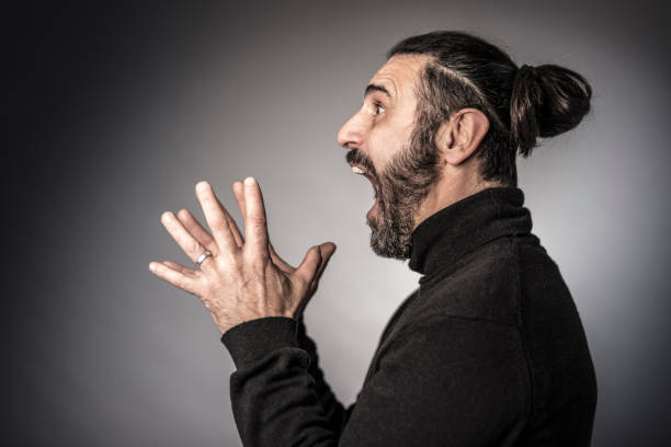 Side View Of Angry Man Screaming While Standing Against Gray Background  mouth open human face shouting screaming stock pictures, royalty-free photos & images