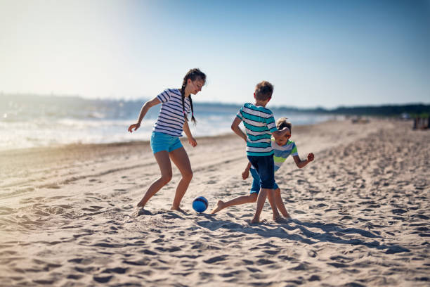 niños jugando al fútbol en la playa - beach football fotografías e imágenes de stock