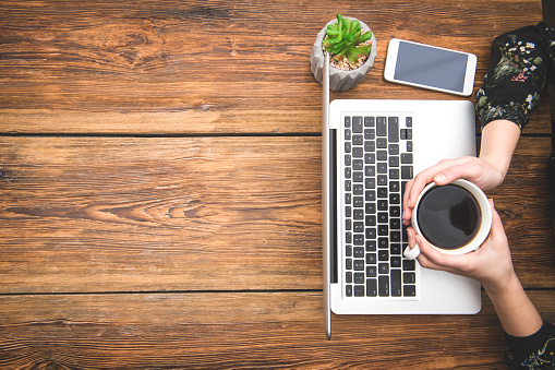 Coffee and laptop on wooden table with space on text.