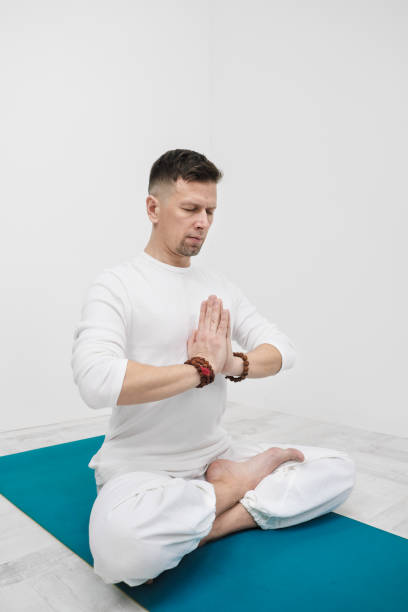 istock A man in white clothes on a white background with his hands folded on his chest. Meditation and prayer, yoga. 1130930343