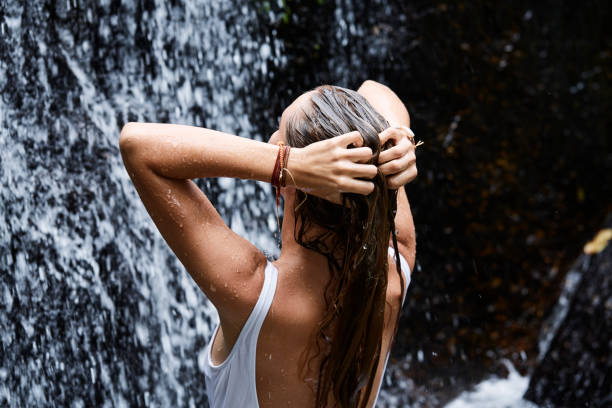 Washing hair in waterfall Young woman washing hair in waterfall, rear view washing hair stock pictures, royalty-free photos & images