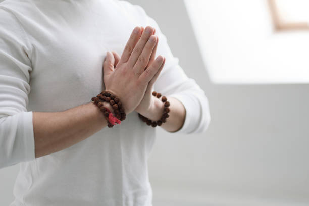 istock A man in white clothes on a white background with his hands folded on his chest. Meditation and prayer, yoga. 1130931932