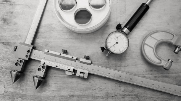 Metal measuring instruments on a wooden table. Product quality control. Metal measuring instruments on a wooden table. Product quality control. Black and white. micron stock pictures, royalty-free photos & images