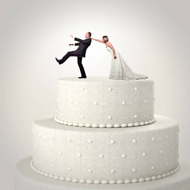 istock Digital Composite Image Of Bride Pulling Bridegroom On Wedding Cake Against White Background 1130935490
