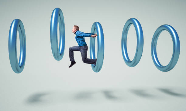 istock Digital Composite Image Of Man Jumping Amidst Rings Against Gray Background 1130936257