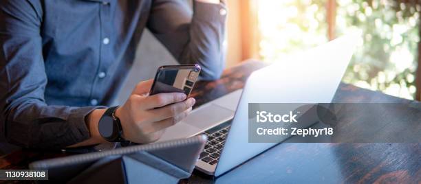 Male Hand Holding Smartphone Businessman Using Laptop Computer And Digital Tablet While Working In The Cafe Mobile App Or Internet Of Things Concepts Modern Lifestyle In Digital Age Stock Photo - Download Image Now