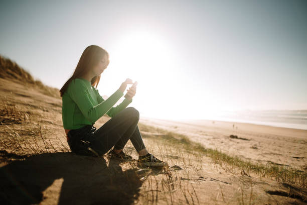istock Young woman at a beach using a smartphone 1130941140