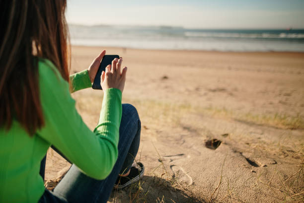 istock Young woman at a beach using a smartphone 1130941393