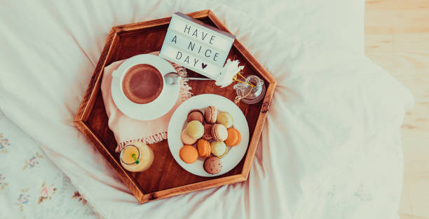 istock Top view Breakfast in bed with Have a nice day text on lighted box. Coffee, juice, macaroons on wooden tray. Good morning mood. Hospitality, care, service concept. Vintage tonning. Wide banner. 1130942975