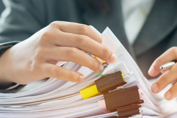 istock Accounting planning budget concept : Business woman offices working for arranging documents unfinished stack of document papers with pen, calculator, clip papers on busy office desk 1130945807