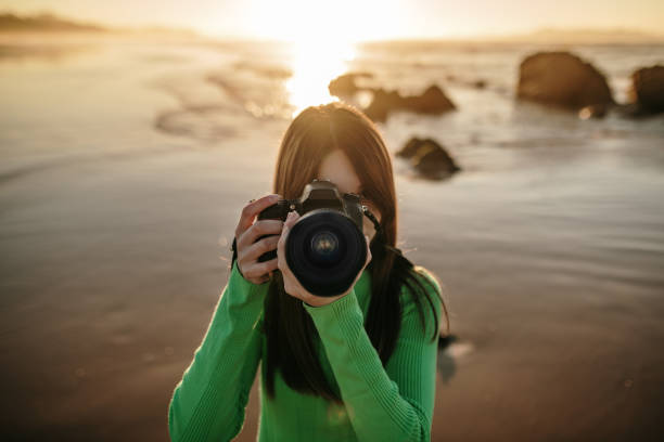 istock Young woman using a modern DSLR camera at a beach 1130949730
