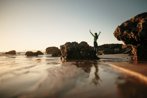 istock Young woman with arms raised at sunset 1130950687
