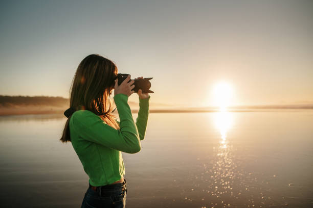 istock Young woman using a modern DSLR camera at a beach 1130951437