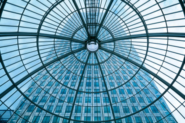 Office building seen through glass roof, glass ceiling in public building, low angle below, Canada Tower, financial district in Canary Wharf, blue toned image, London, England, UK.