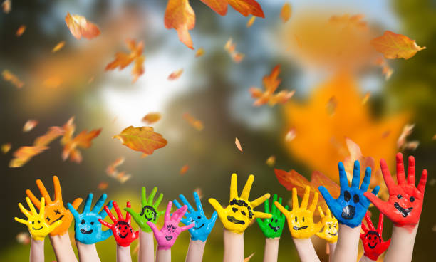 falling leaves and many painted kid hands on autumn background