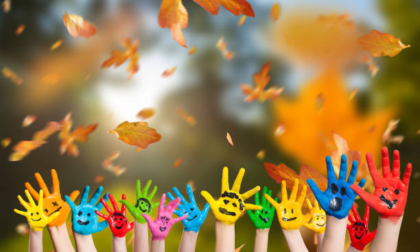 falling leaves and many painted kid hands on autumn background stock photo