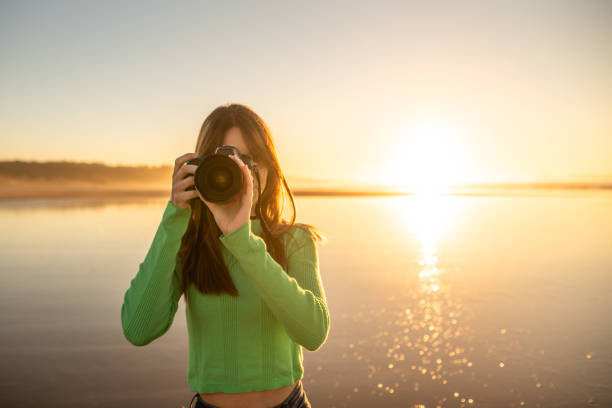 istock Young woman using a modern DSLR camera at a beach 1130952996