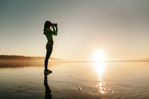 istock Young woman using a modern DSLR camera at a beach 1130953236