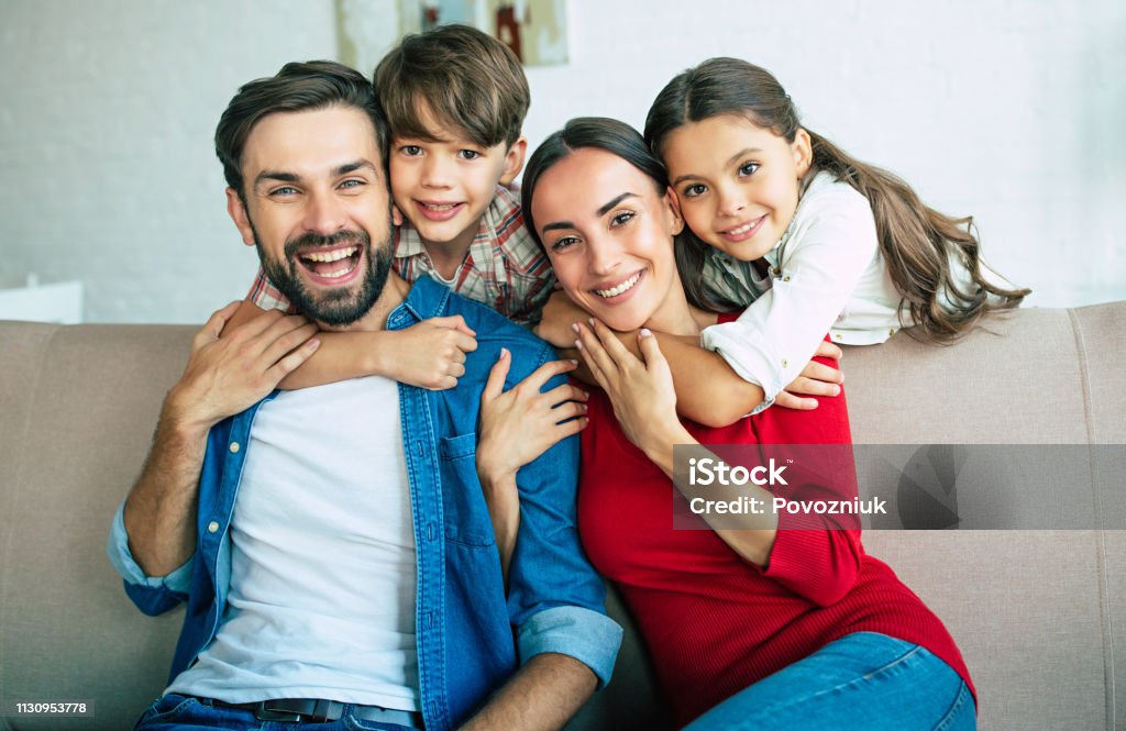 Junge glückliche Familie entspannt sich zu Hause lächelnd und umarmt - Lizenzfrei Familie Stock-Foto