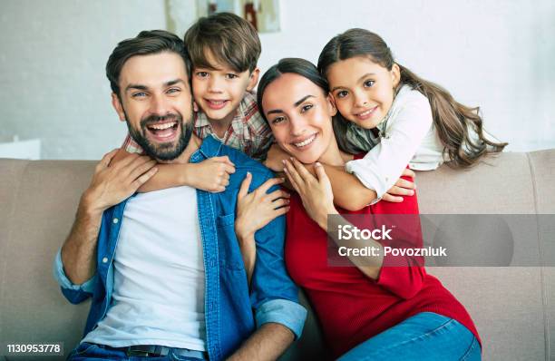 Young Happy Family Relax Together At Home Smiling And Hugging Stock Photo - Download Image Now