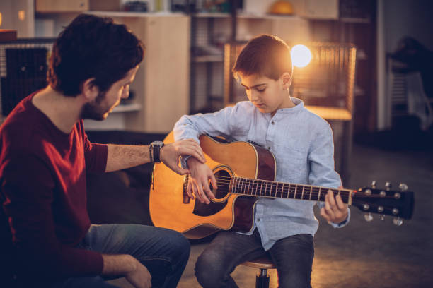 istock Young boy in guitar school with teacher 1130956133