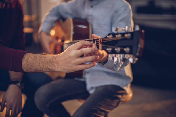 istock Young boy in guitar school with teacher learning to play 1130956171