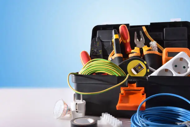 Photo of Toolbox full of tools and electrical equipment on white table