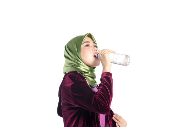 istock Woman Drinking Water While Standing Against White Background 1130958332