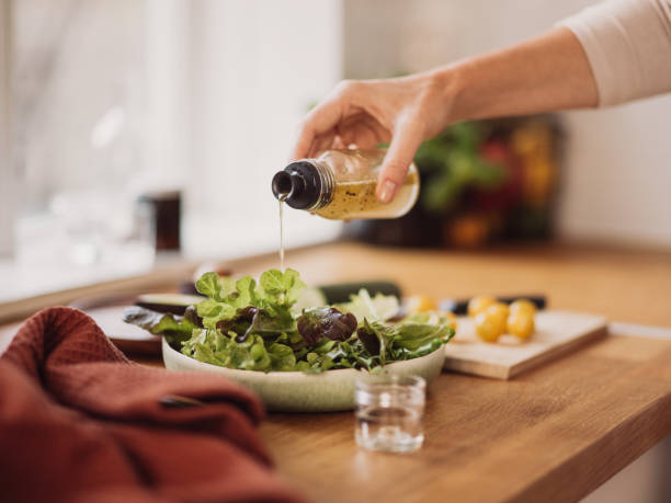 femme préparant la salade saine dans la cuisine - condiment healthy lifestyle vinegar cooking oil photos et images de collection