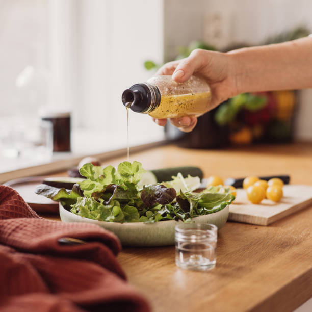 mujer preparando ensalada sana en la cocina - condiment healthy lifestyle vinegar cooking oil fotografías e imágenes de stock