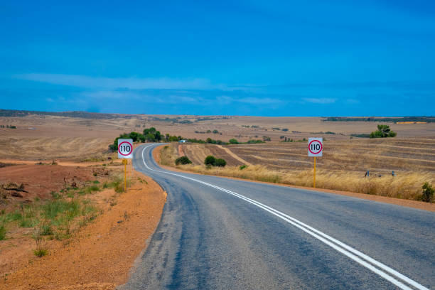 Australian bush road leading through dry landscape and farmland with speed limit 110 kph stock photo