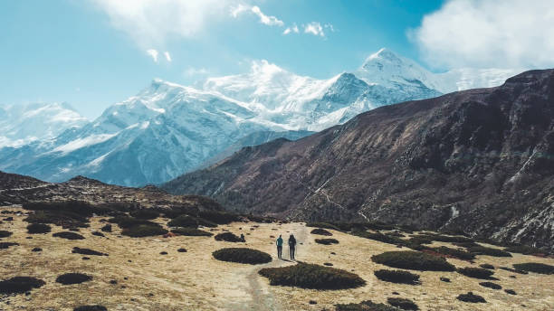 nepal - couple walking in manang valley - himalayas mountain aerial view mountain peak imagens e fotografias de stock