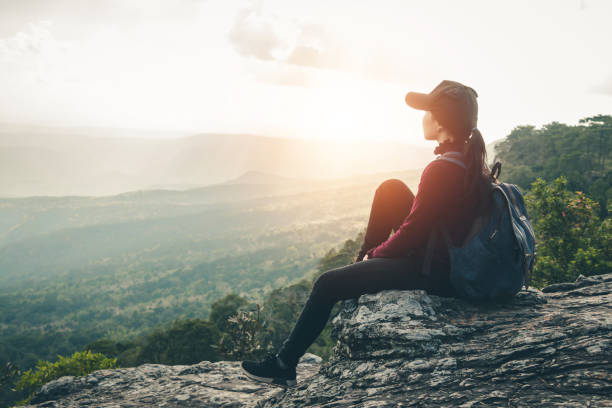 istock Side View Of Woman Looking At Landscape While Sitting On Cliff Against Sky During Sunset 1130964085