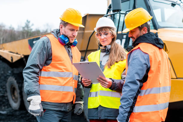 istock Three workers in a quarry discussing in front of heavy machinery 1130966257