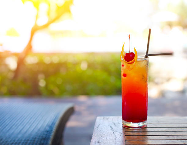 Glass with a bright tequila sunrise cocktail . Luxury resort on tropical island