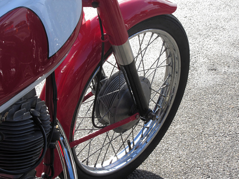 Classic motorcycle standing on the road . Closeup of motorbike front wheel