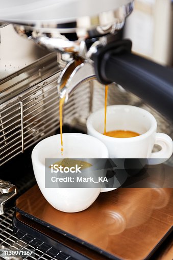 istock Coffee brewing in coffee machine. Espresso pouring in two cups. 1130971367