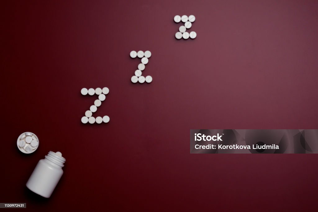 Pills. White sedative tablets on a red background, lined with the letter zzz, with a bottle Antibiotic Stock Photo